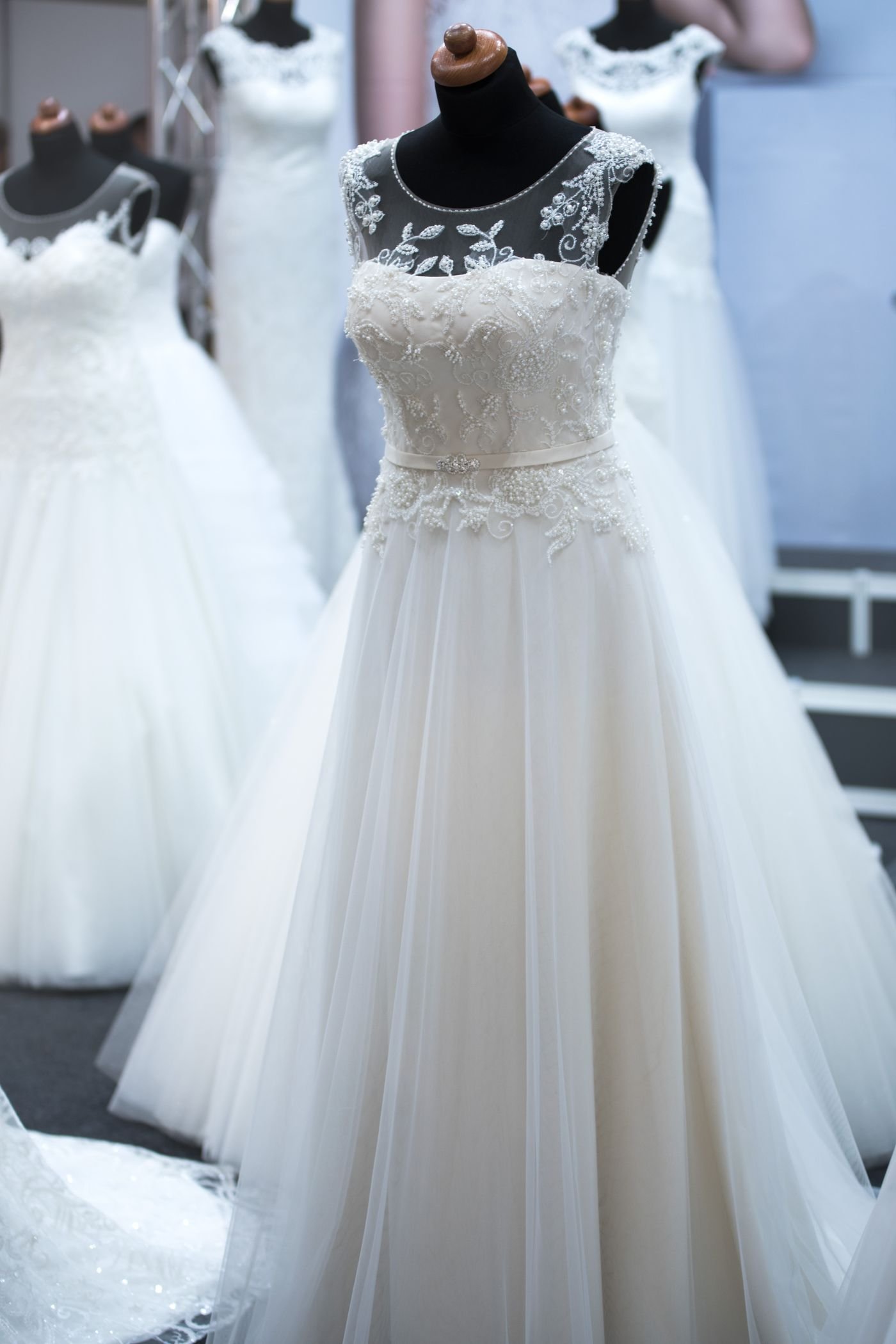 White ballgown with a beaded bodice on a mannequin, tulle skirts behind it.